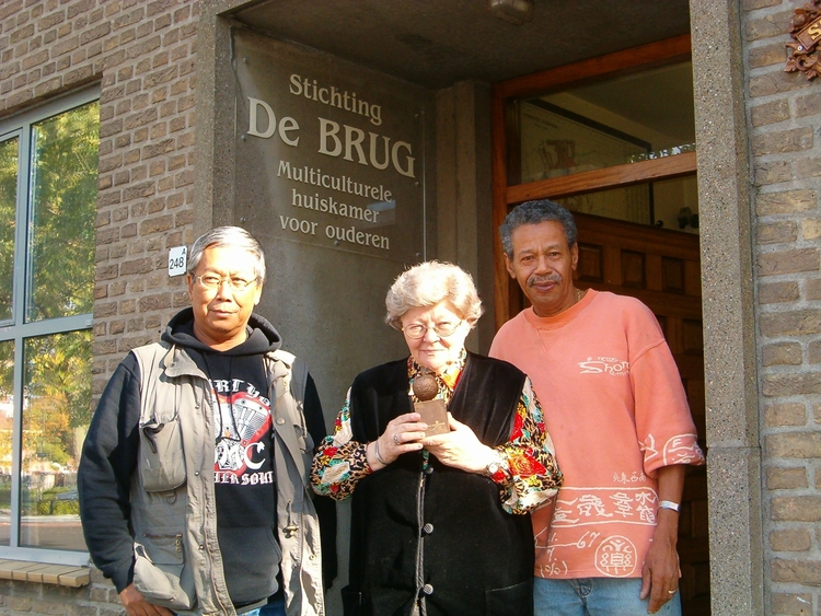 Foto van vrijwilligers wie, wat, wanneer, waar Van links naar rechts Wil, Marie en Ed. Marie houdt het Appeltje van Oranje vast. 