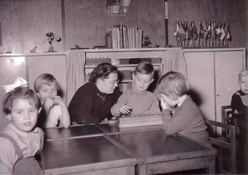  Foto: Collectie Joost van Ingen Juffrouw De Bunje van de Montessori-kleuterschool aan het Surinameplein in schooljaar 1955-56. Ik zit op de foto rechts van haar - Foto: Collectie Joost van Ingen 