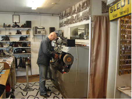 Hans Las van Bennekom aan het werk achter de poetsmachine. Het ruikt in zijn zaak naar een mengsel van gestoomde kleding en vers geraspte schoenzolen. Alleen de sleutels zijn reukloos. Foto: Jan Wiebenga, 20 oktober 2008 