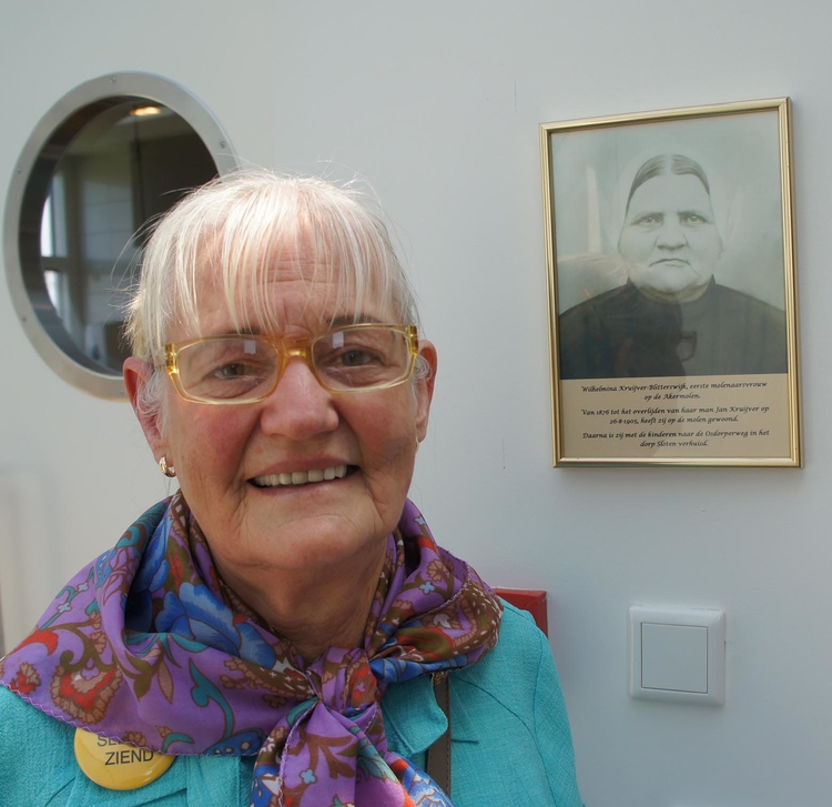 Gerda van der Linde in de Akermolen naast een foto van een vrouw in klederdracht Foto: Shirley Brandeis, juni 2013 